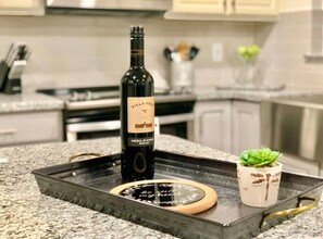 Una encimera de cocina con una botella de vino, una bandeja y una pequeña planta en maceta.