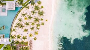 Eine Vogelperspektive eines Strandresorts mit Pool, Palmen und freiem Blick auf den Ozean.
