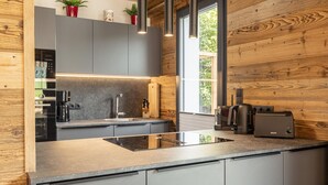 Une cuisine moderne avec des meubles gris, une plaque de cuisson à induction noire et une machine à café.