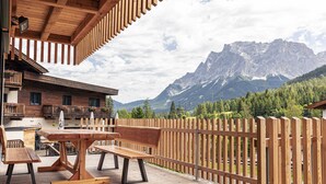 Une terrasse en bois avec une table et des bancs, offrant une vue sur un paysage montagneux.