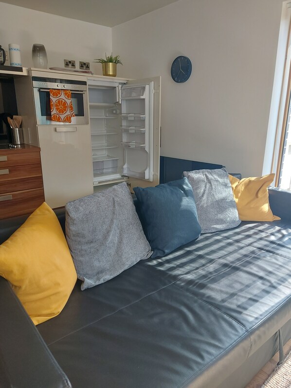 Relax in this inviting living space with a sofa, refrigerator, and window offering a view.