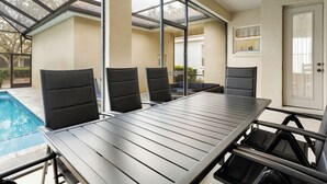 Ein überdachter Patio mit Pool, einem Tisch mit Stühlen und einer Tür mit Fenster.