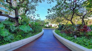 Guests can stroll along the beautifully maintained pathway, lined with lush greenery and mature trees, to reach their accommodations.