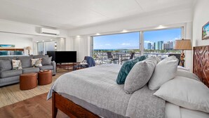 Ett rymligt hotellrum med en stor säng, en soffa, en TV och en balkong med utsikt över staden.