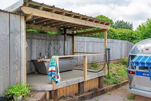 A wooden outdoor shower area with a bench, a towel, and a hose. - Airstream, Devon Hideaways - a shepherds hut that sleeps 2 guests in 1 bedroom (Kenn)