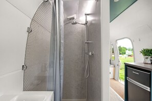 A modern bathroom with a shower, a toilet, and a sink. - Airstream, Devon Hideaways - a shepherds hut that sleeps 2 guests in 1 bedroom (Kenn)