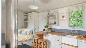 A compact kitchen with white cabinets, a wooden countertop, and a window with green foliage outside. - Apple Blossom, Hot Tub,Woodburner (Kenn)