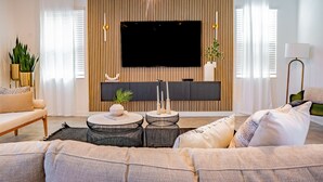 Un salon moderne avec un téléviseur à écran plat fixé à un mur en bois, un canapé, une table basse et une lampe.