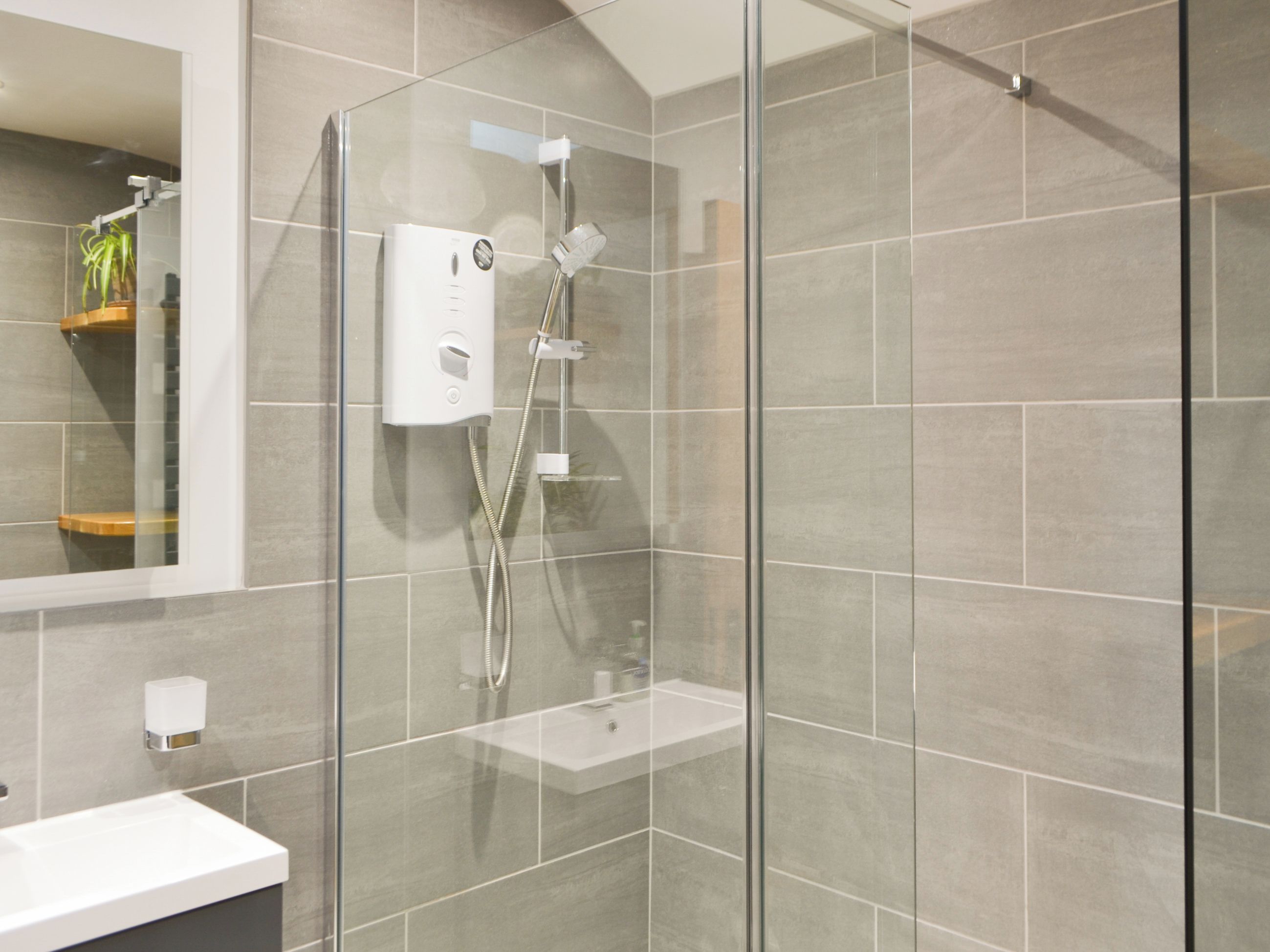 A modern bathroom with a glass-enclosed shower, a white sink, and a mirror.