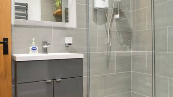Une salle de bain moderne avec une douche à parois de verre, un lavabo blanc et un miroir au-dessus.