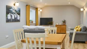 Una sala de estar moderna con comedor, televisor de pantalla plana y sofá.