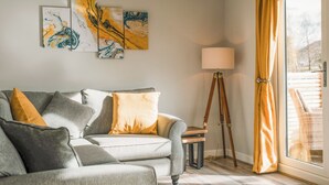 A living room with a grey sofa, yellow cushions, and abstract wall art. - Swallow Lodge - UK42540 (Clifford)