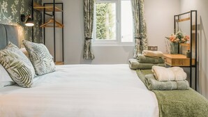 A bedroom with a bed, a bedside table with a mirror, a window with curtains, and a wall-mounted shelf. - Swallow Lodge - UK42540 (Clifford)