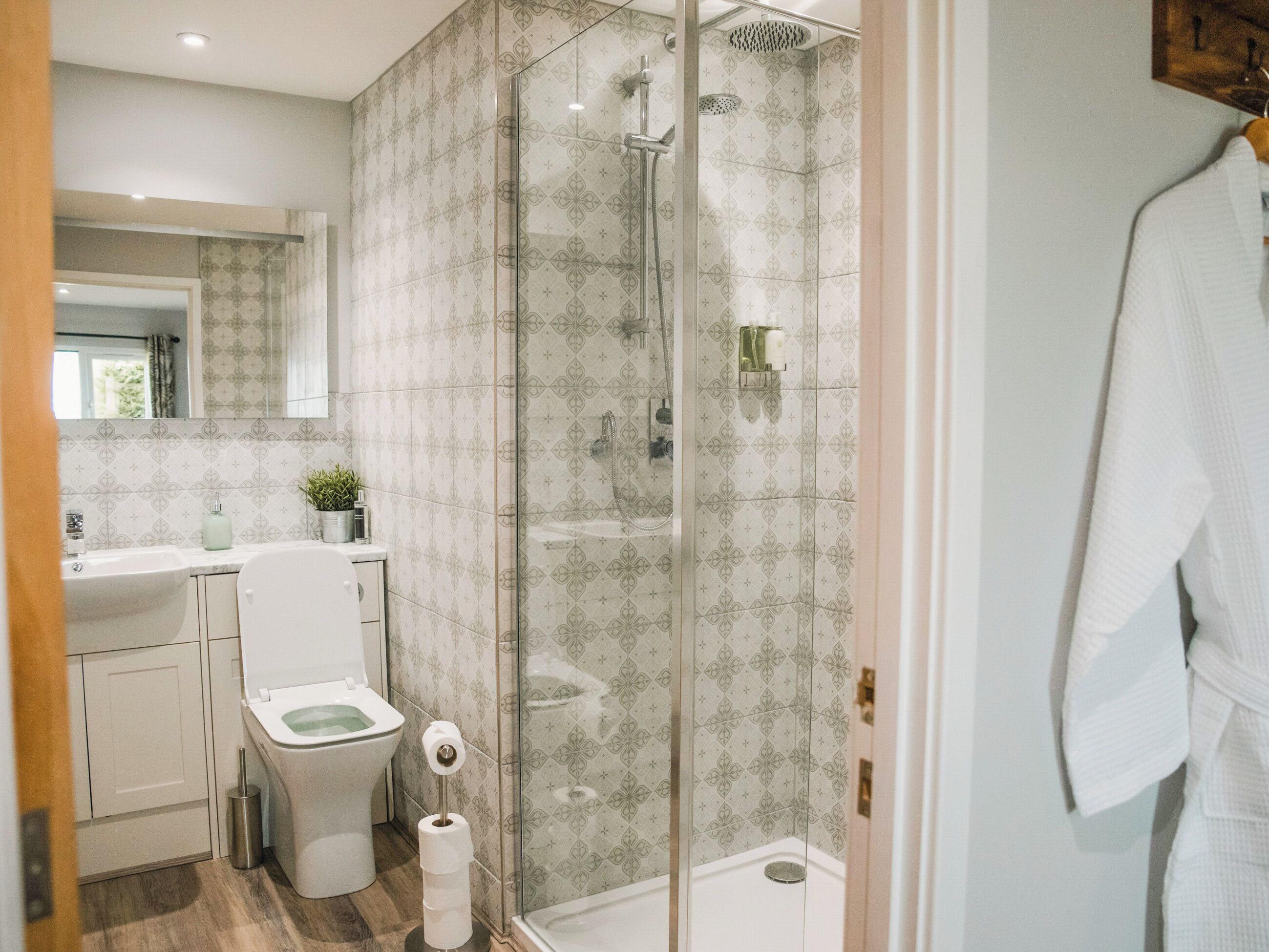 Un baño moderno con cabina de ducha de vidrio, inodoro y lavamanos.