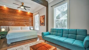 Une chambre à coucher avec un lit, un canapé de couleur turquoise, un plafond en bois et une fenêtre avec des stores.