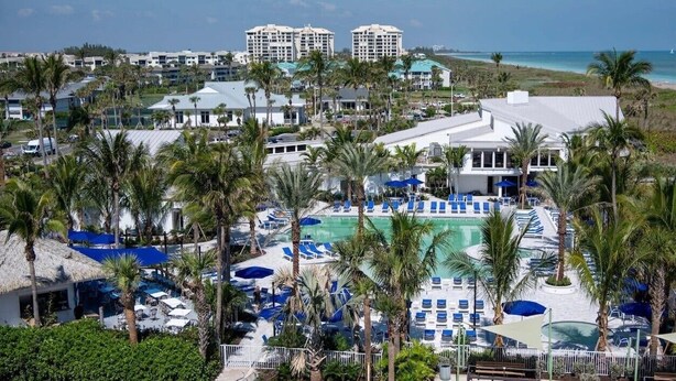 A resort with a large pool, multiple buildings, and palm trees. - Pet-Friendly Paradise with Special Discounts - A Wave from It All Awaits!" (Fort Pierce)
