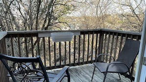 Een houten terras met twee zwarte metalen stoelen en een kleine witte plantenbak.