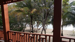 Una terraza de madera con vista a una playa y palmeras.