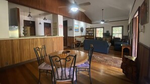 Un amplio salón con una mesa de comedor y sillas, un sofá y una estantería.