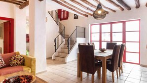 A spacious living area with a wooden dining table, a sofa, and a staircase leading to an upper floor. - Fantastic rural house in Nigüelas (Nigüelas)