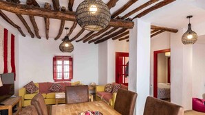 A cozy living room with a wooden dining table, colorful cushions, and a red door. - Fantastic rural house in Nigüelas (Nigüelas)