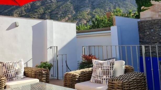 A terrace with wicker furniture, a glass table, and a red umbrella. - Fantastic rural house in Nigüelas (Nigüelas)