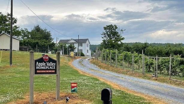A sign for Apple Valley Homeplace with a gravel path leading to a house.