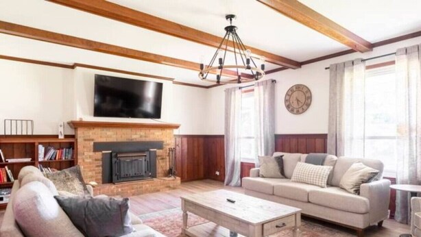 Una sala de estar con chimenea, sofá, mesa de centro y televisor montado en la pared.