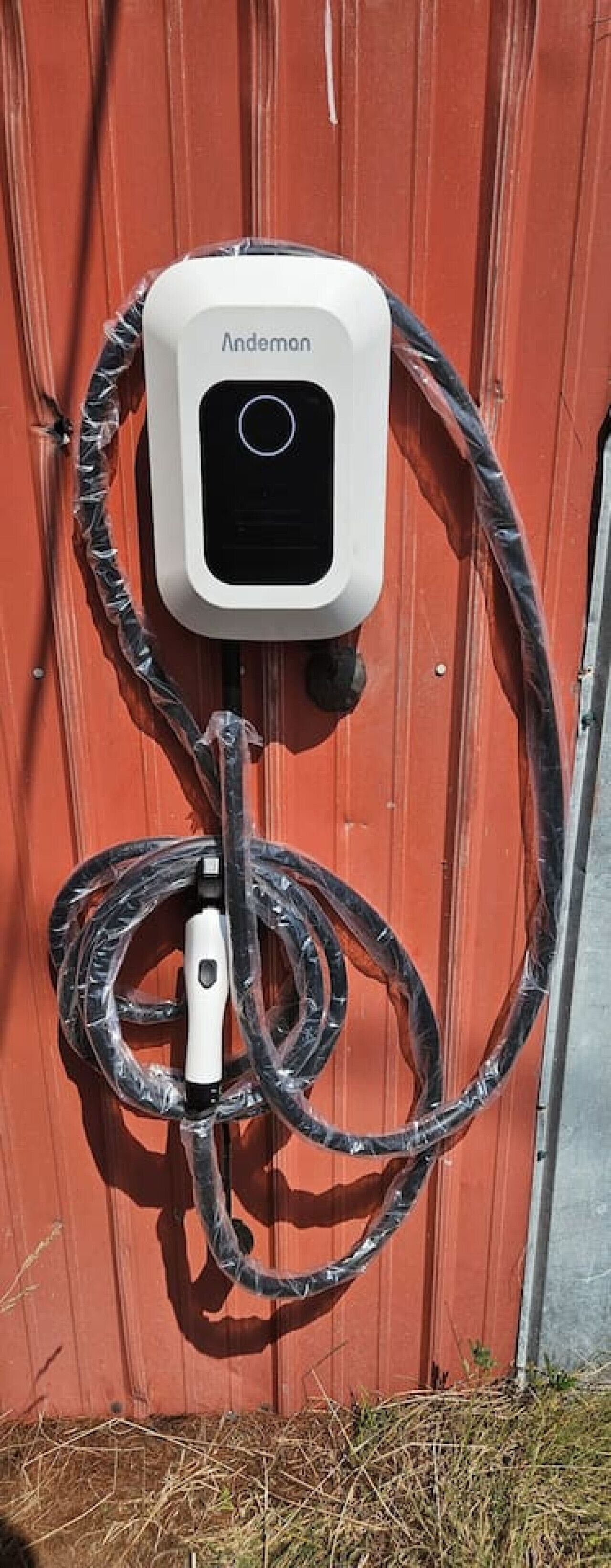 Un dispositivo Andemon portátil montado en una pared roja con cables enrollados.