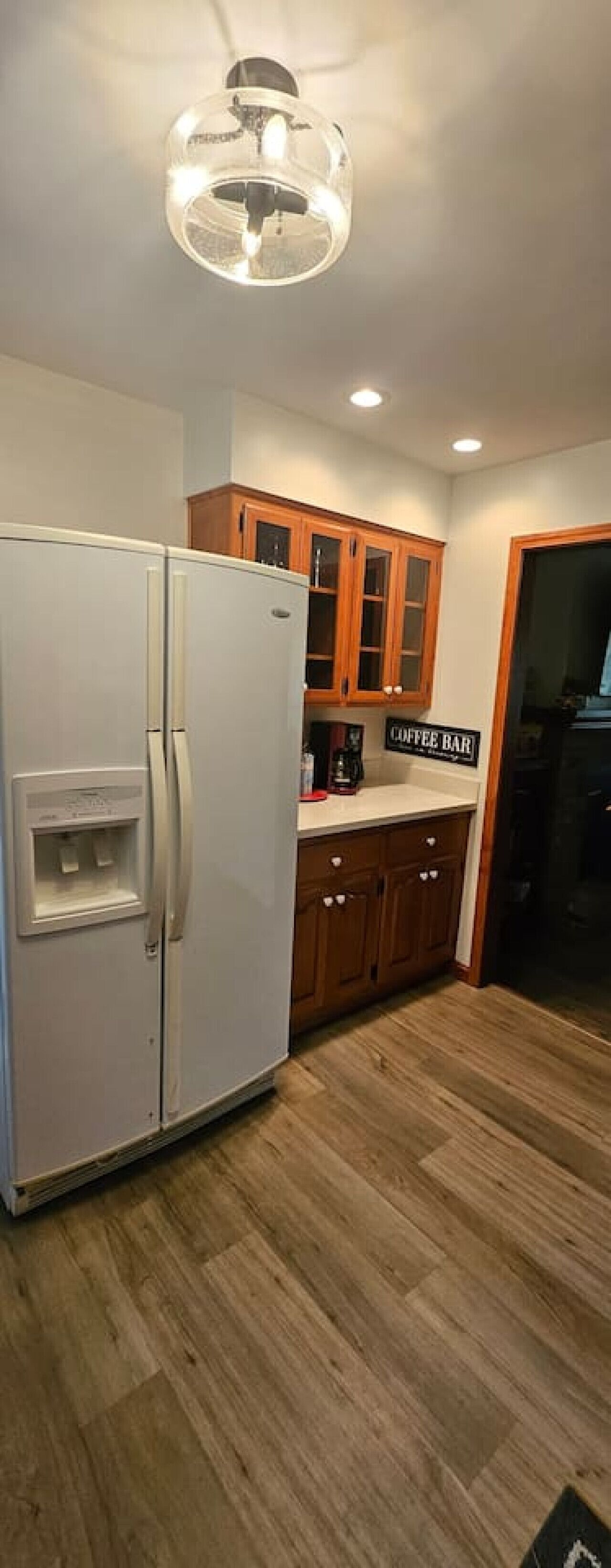 A kitchen with a white refrigerator, wooden cabinets, and a coffee bar sign.