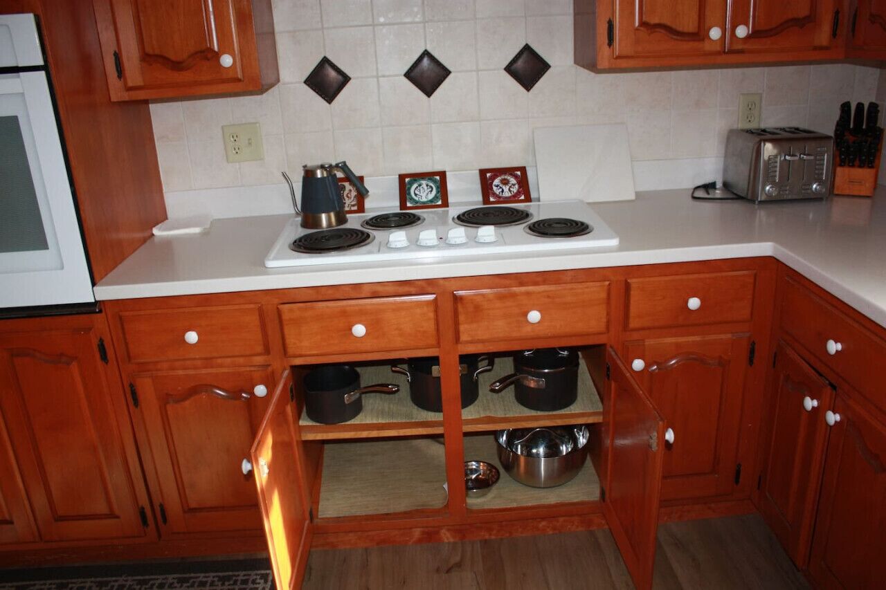A kitchen with wooden cabinets, a white countertop, a stove, and a toaster.