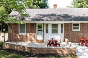 A brick house with a covered patio, a door, and a window. - 85 acre private estate (Logan)