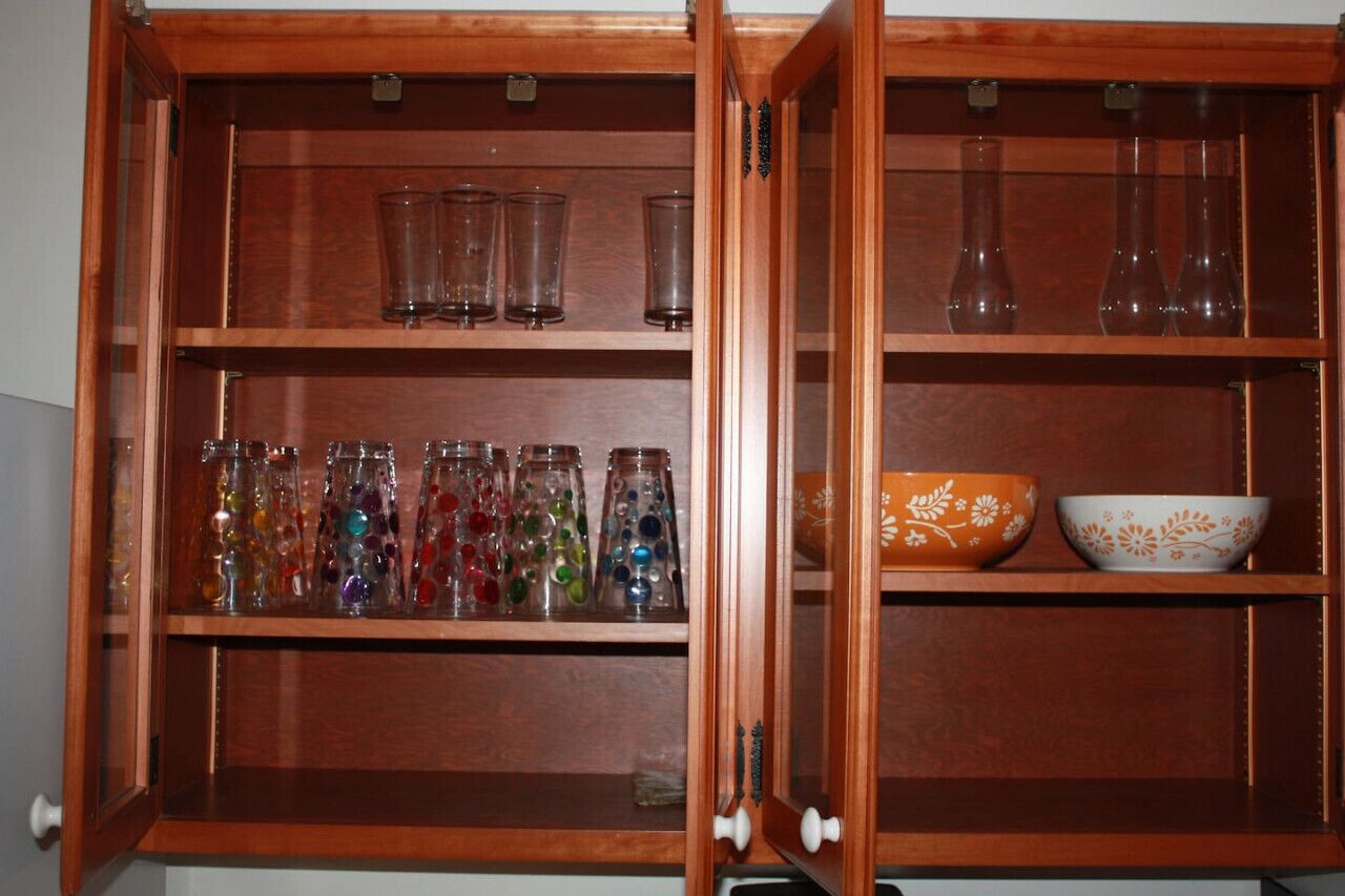 Un meuble en bois doté de plusieurs étagères, contenant des bocaux en verre, des verres transparents et des bols décoratifs.