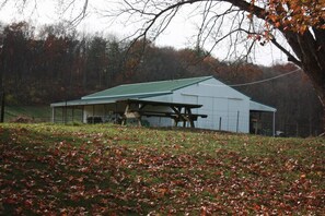 A large, single-story building with a green roof and a covered picnic table in front. - 85 acre private estate (Logan)