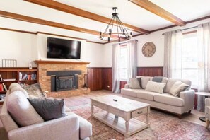 Una sala de estar con chimenea, sofá, mesa de centro y televisor montado en la pared.