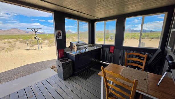 Una cocina con estufa a gas, un lavamanos y ventana con vistas a un paisaje desértico.