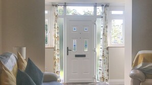 Une pièce avec une porte blanche, des rideaux à motifs, un canapé et un fauteuil.