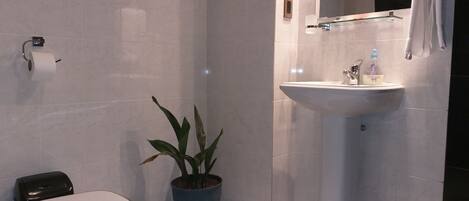 Un baño con inodoro, lavamanos y una planta en maceta.