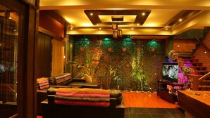 A cozy living area with a sofa, TV, and a stone wall with plants. - Hostal Cagnapa Restobar (Uyuni)
