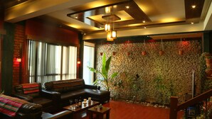A modern living room with a stone wall, leather sofa, and potted plants. - Hostal Cagnapa Restobar (Uyuni)