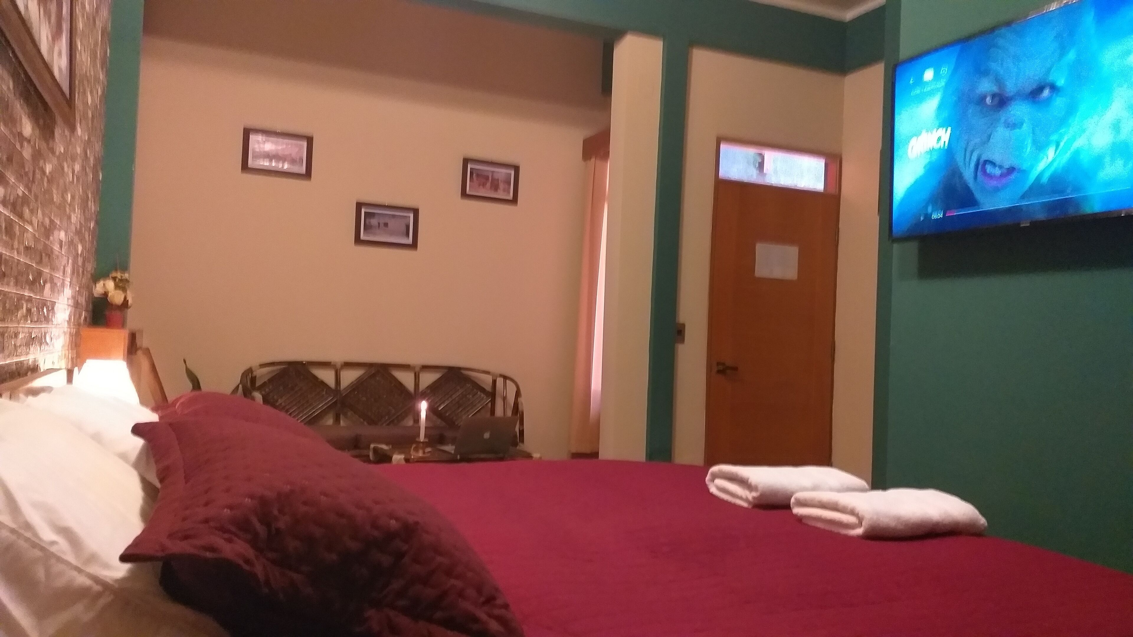 Una habitación de hotel con una cama, un televisor montado en la pared y dos cuadros enmarcados.