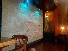 Interior de restaurante con mural de pared de ladrillo, mobiliario de madera e iluminación ambiental.