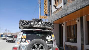 Un vehículo estacionado frente a un edificio con un letrero que dice "Hostal Canapa Restobar".
