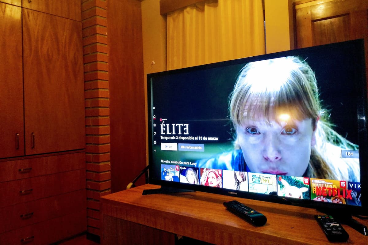 Un televisor sobre un soporte de madera con un control remoto a su lado.