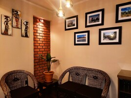 Un comedor con sillas de mimbre, pared de ladrillo y cuadros en la pared.