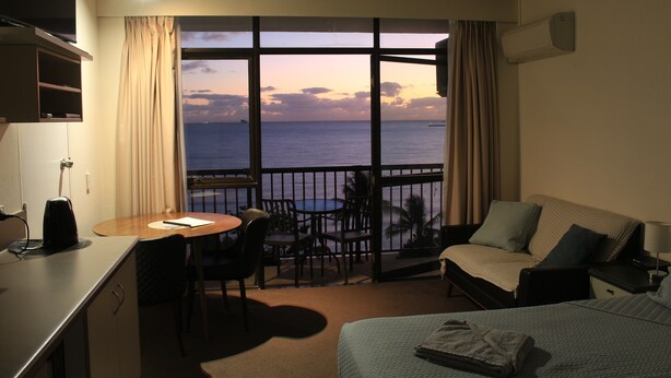 Una habitación de hotel con balcón, cama, escritorio y zona de comedor.