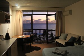 A hotel room with a balcony, a bed, a desk, and a dining area. - Beautiful Beachfront location. (North Ward)
