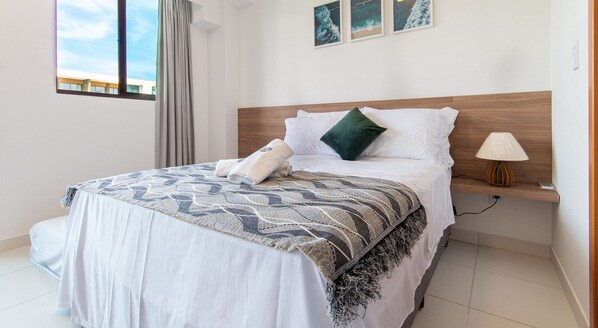A neatly made bed with a patterned blanket, pillows, and a bedside lamp.