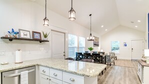 A modern kitchen with granite countertops, white cabinets, and pendant lighting. - 1 Mi to Beach: Retreat w/ Large Yard in Rockport (Rockport)