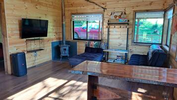 L’intérieur chaleureux d’un chalet, avec un décor en bois, un téléviseur fixé au mur, un canapé, une table et une cheminée.